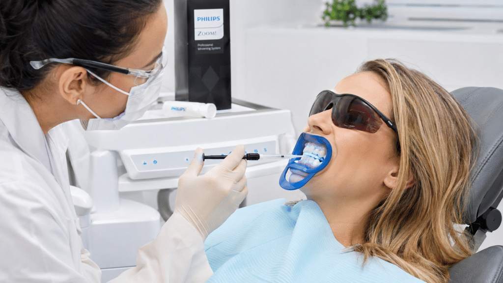 Patient receiving supervised in-chair teeth whitening treatment at a dental clinic.