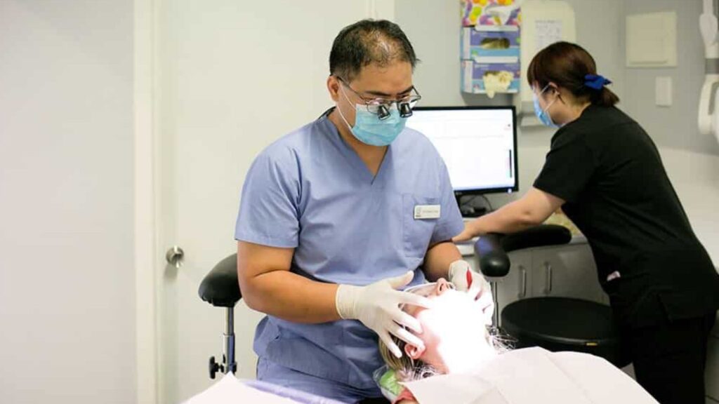 Dentist performing a scale and clean to prepare a patient's teeth for whitening.